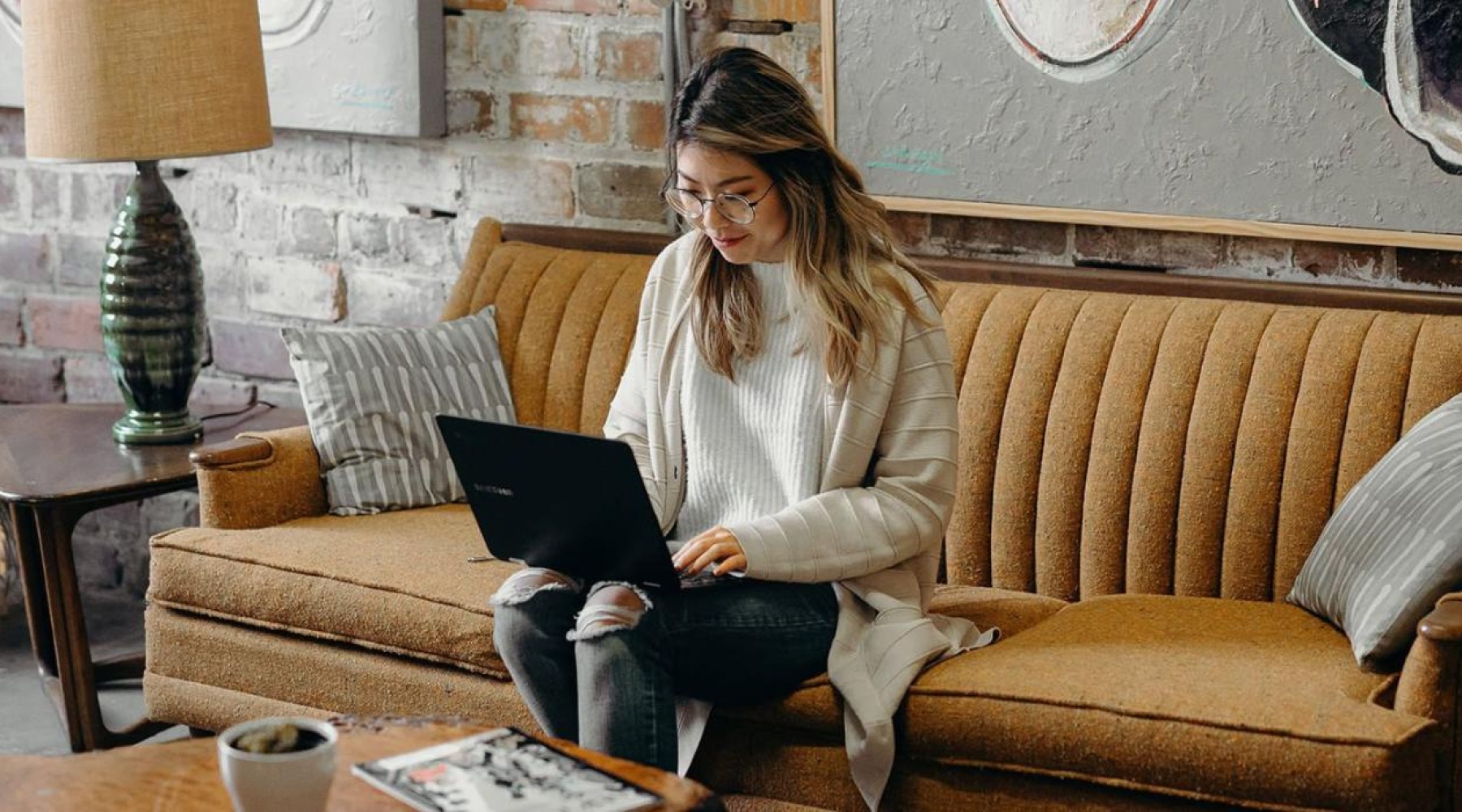 a woman sitting on a couch working on a laptop