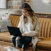 a woman sitting on a couch working on a laptop